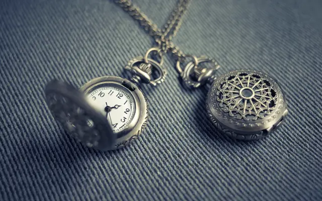 Two antique pocket watches resting on dark denim fabric