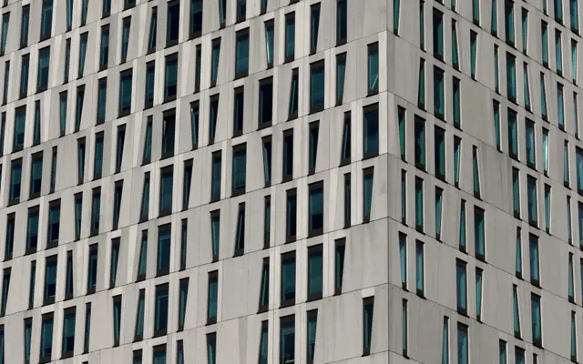 White high-rise facade with rows of angled narrow windows