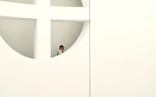 Man standing in a round opening of a white modern building